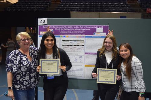 (From Left to Right) Dr. Lisa Oakes, Franchesca, Emily, and Van in front of their poster at the Undergraduate Research Conference
