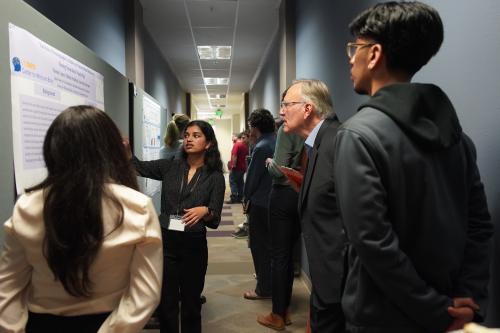 Nikhita, Lino, and Fatima presenting their poster to the Director of the CMB, Ron Mangun