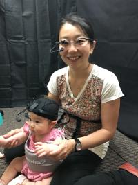 A mom and sitting with her baby. Both are wearing positive science eye trackers on their heads